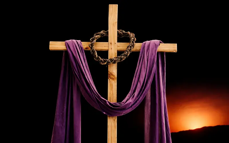 Wooden cross draped with purple cloth and crown of thorns during Lent